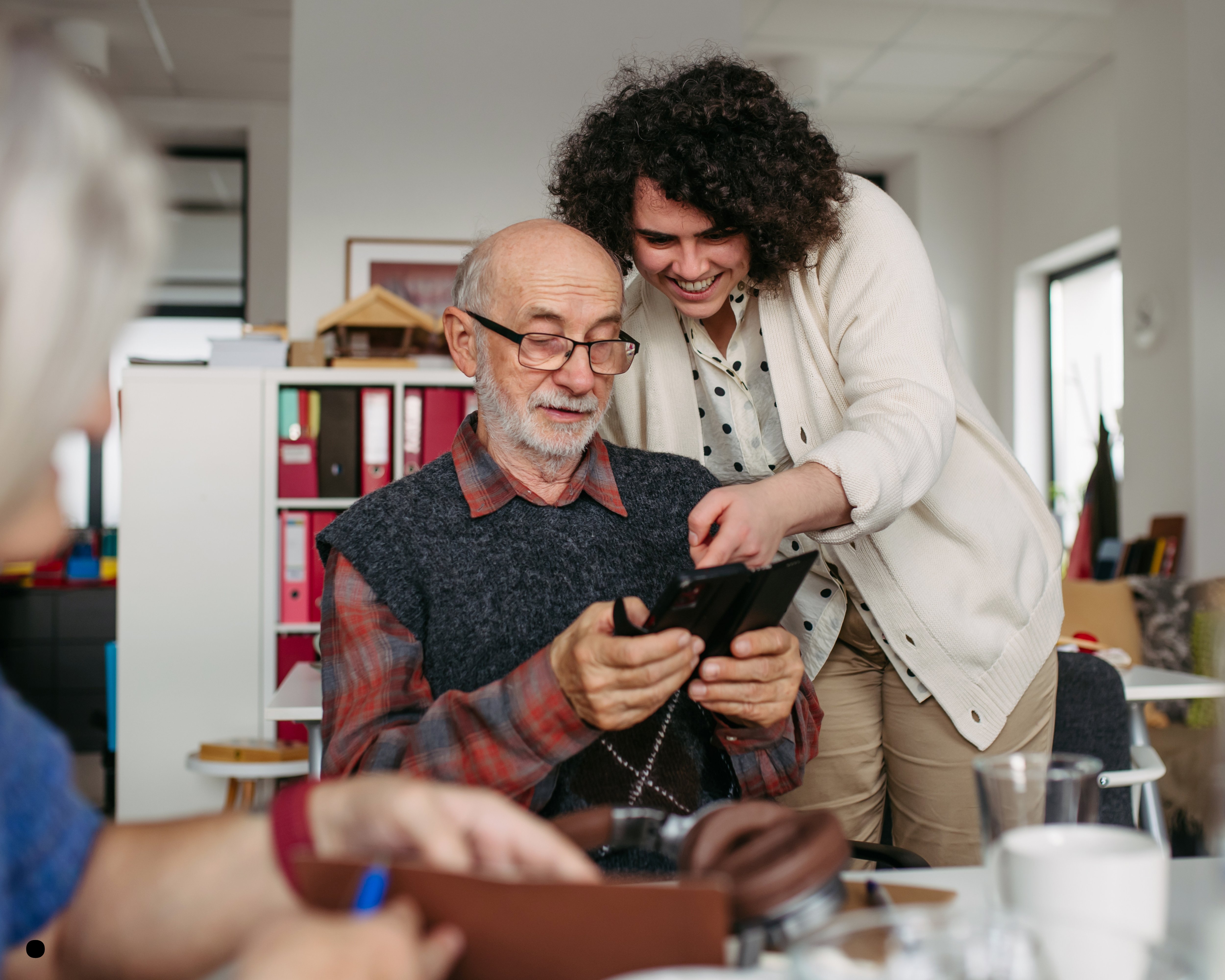 Accompagnant aidant une personne âgée avec un smartphone — illustration du cours DEAES numérique